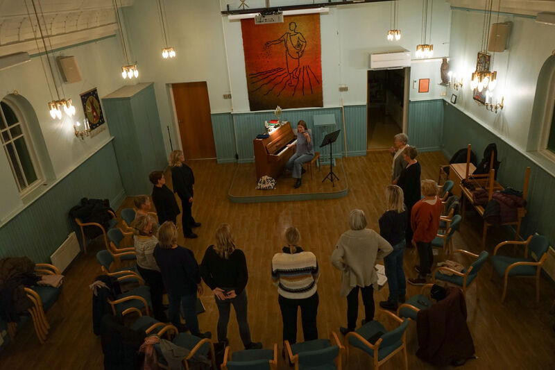 Dirigent Astrid Willumsen spiller piano og leder en oppvarmingsøvelse for koret.