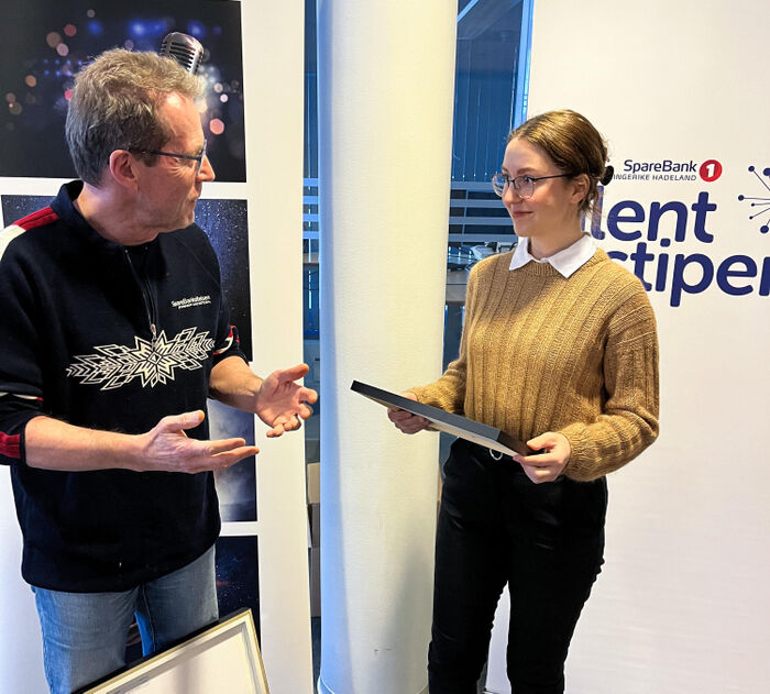 Bjørn fra SpareBank 1-stiftelsen Jevnaker Lunner Nittedal overrekker stipend, bilde og blomster